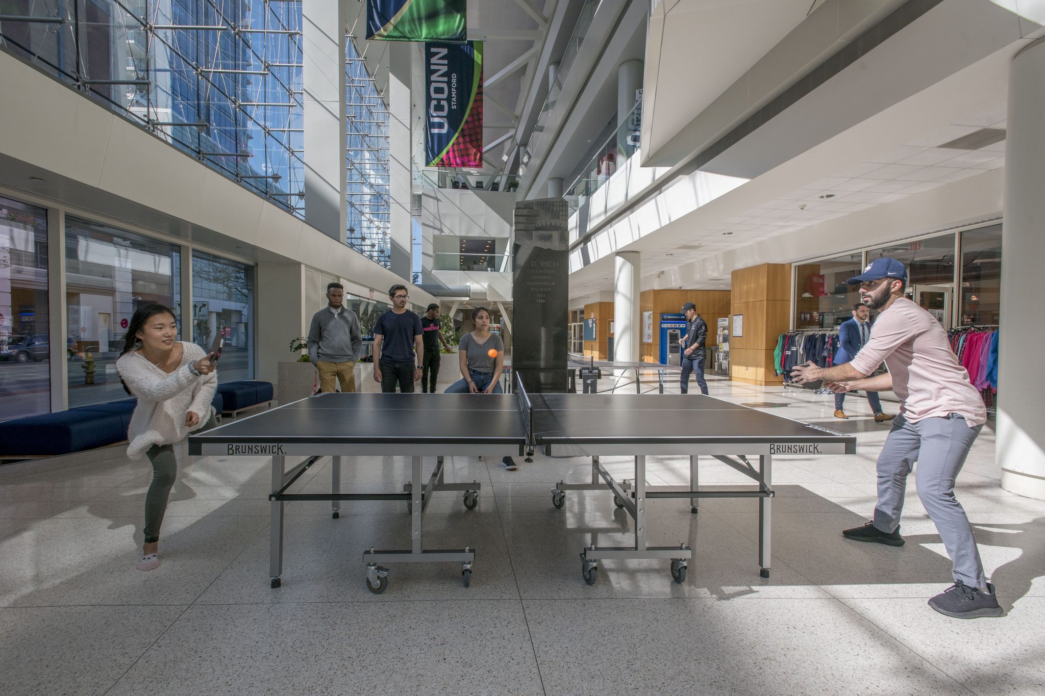 Students playing ping-pong in the concourse (atrium) at UConn Stamford 