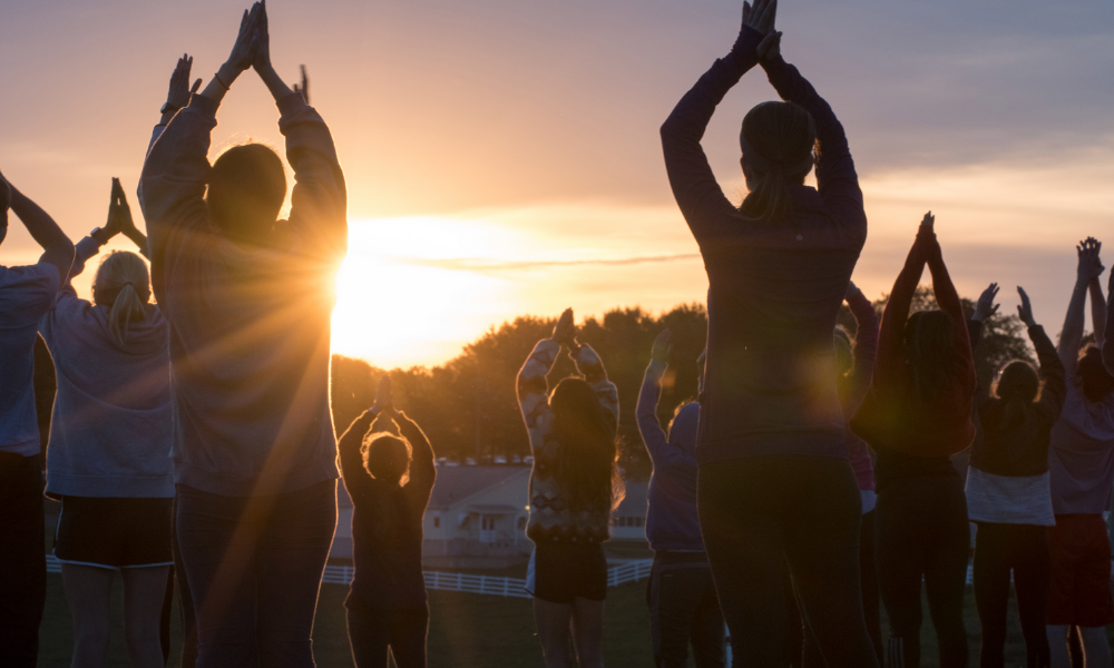 Young adults doing sunrise yoga outside